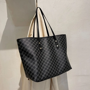 Detailansicht des Monogramm-Musters auf dunkelgrauer Tasche mit Ledergriffen