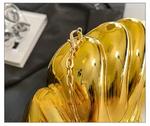 Detail of high-gloss gold evening bag with metallic finish and fine chain hardware