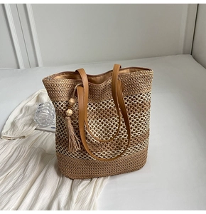 Detail of straw tote bag with intricate hollow weave texture and brown leather straps