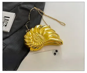 Golden nautilus seashell evening bag shown with phone to highlight its compact size