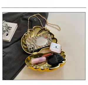 Detail showing the internal capacity of the gold shell clutch with phone and lipstick