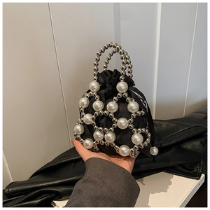 Détail de maille de perles ajourée sur pochette en satin noir avec anse élégante