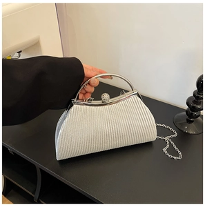 Detailed silver clutch bag featuring vertical pleats and a large rhinestone clasp handle