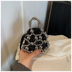 Détail d'un mini sac tissé de perles argentées avec doublure en satin noir chic
