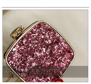 Detail of rose gold sequin clutch bag with metallic frame and textured surface