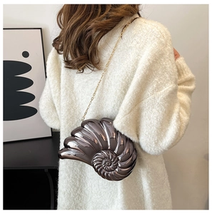 Detail of shell-shaped hardshell shoulder bag with metallic finish and gold chain strap