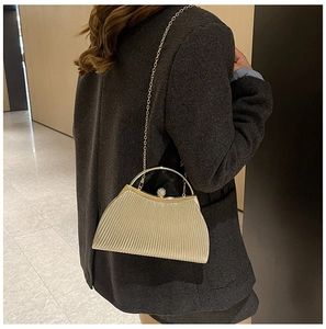 Champagne gold pleated evening clutch with crystal clasp shown on grey blazer