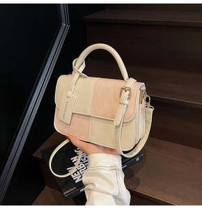 Detail of a vintage-style patchwork handbag with elegant top handle and logo tag
