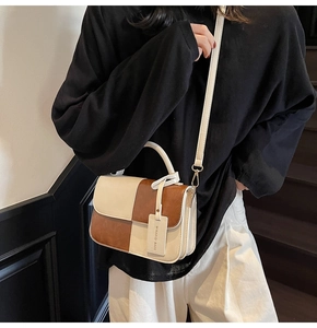 Detail of vintage bicolor crossbody bag with leather tag and adjustable shoulder strap