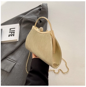 Detail of golden pleated evening bag with metallic handle and diamond clasp on grey blazer