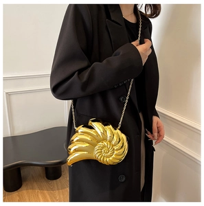 Fashionable gold seashell clutch bag with metallic chain strap worn by a model in black suit