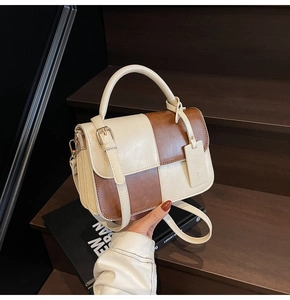 Detail of the stitching and golden buckle on the retro two-tone crossbody leather bag