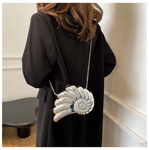 Detail of silver metallic shell-shaped crossbody bag with polished mirror finish and chain