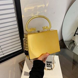 Golden acrylic box bag featuring ornate dragon handle and detachable metal chain strap
