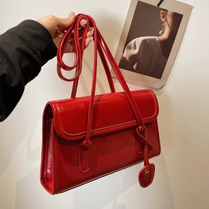 Detail view of red glossy patent leather shoulder bag with cute heart-shaped charm