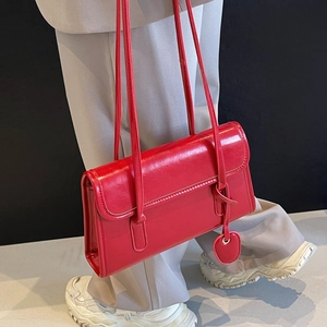 Macro shot of red glossy leather shoulder bag with matching heart-shaped charm accessory