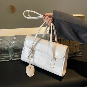 Detailed macro view of white rectangular faux leather shoulder bag with oval charm