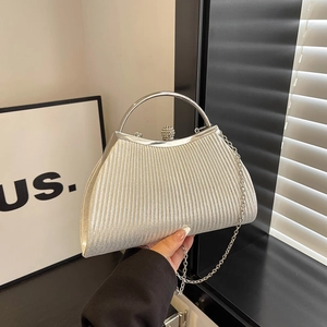 Chic silver pleated evening bag with ring handle and rhinestone clasp shown in hand
