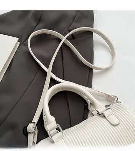 Detail of white pleated texture handbag with adjustable strap on a grey blazer