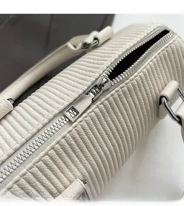 Detailed macro view of smooth silver metal zipper on pleated cream-white pillow handbag