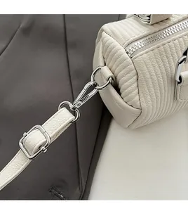 Detail of detachable silver metal hook and vertical quilted texture on off-white bag