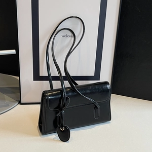 Detail of black rectangular baguette bag featuring glossy PU leather and heart charm