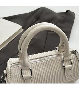 Close-up of cream bowling bag showing vertical pleat texture and silver hardware details