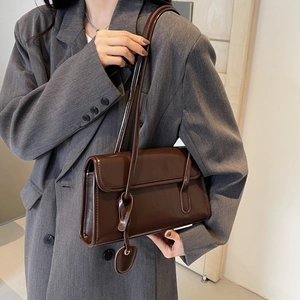 Detail of vintage brown rectangular shoulder bag with heart pendant on grey suit