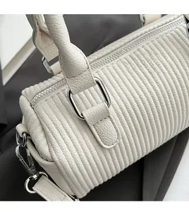 Detail of white lychee leather texture and silver hardware on a cylinder handbag