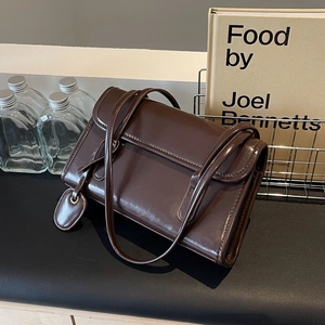 Detail of a dark brown glossy vintage baguette bag with a sleek rectangular flap design