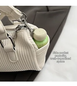 Close-up of side pocket on beige pleated handbag holding a small water bottle