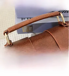 Macro view of brown leather Boston bag showing floral embroidery and fine grain texture