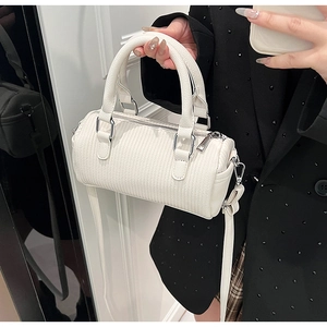 Close-up of white boston bag with pleated texture held by model in black suit