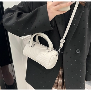 Detailed view of white pleated boston bag with silver hardware and adjustable strap