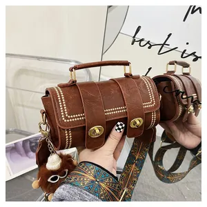 Detail of vintage brown cylinder bag with gold rivets and embroidered jacquard strap