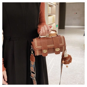 Close-up of retro brown Boston bag with gold studs and patterned wide shoulder strap