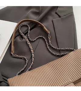 Detail of vertical pleated brown leather tote with silver metal chain and shoulder strap