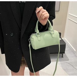 Detail of mint green barrel bag showing textured leather and silver metal buckles