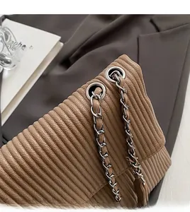 Detail of dark brown pleated tote bag with silver chain strap and metal eyelets