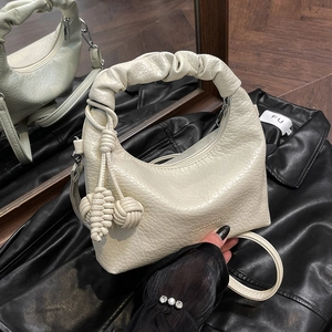 Schicke beige Halbmond-Tasche mit Scrunchie-Griff und dekorativem Kugel-Anhänger