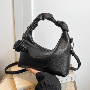 Elegante schwarze Halbmond-Schultertasche mit Faltenhebel und Quastendetails auf Büchern