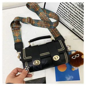 Detail of black leather Boston bag with gold rivets, patterned strap and plush charm