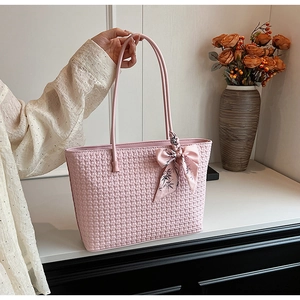 Detail of pink woven tote bag with square texture and a floral silk scarf bow detail