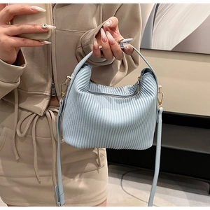 Close-up of light blue pleated texture leather handbag with golden chain buckle and strap