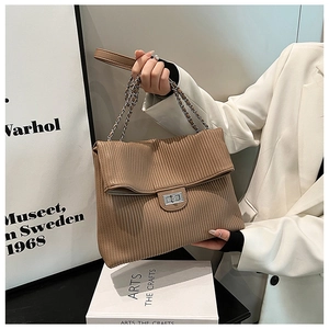 Detail of a brown pleated tote bag with silver metal twist lock and chain strap
