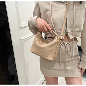 Detail of a beige pleated handbag showing delicate texture and urban minimalist style