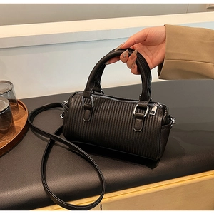 Detailed close-up of a black vertical striped quilted cylinder handbag with silver zipper