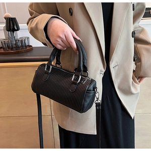 Close-up of a pleated black cylinder handbag with silver hardware and dual handles