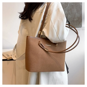 Close-up of brown suede tote bag with minimalist gold hardware and slim shoulder strap
