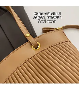 Close-up of brown leather tote featuring vertical pleated texture and fine stitching detail